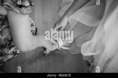 Sposa mette sul matrimonio scarpe sui suoi piedi Foto Stock