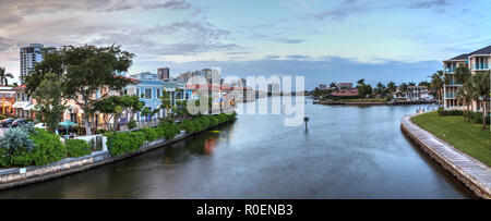 Le luci di Natale incandescenza al tramonto del colorati negozi del villaggio su Venetian Bay in Naples, Florida. Foto Stock