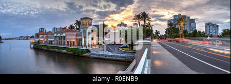 Naples, Florida, Stati Uniti d'America - 3 Novembre 2018: le luci di Natale incandescenza al tramonto del colorati negozi del villaggio su Venetian Bay in Naples, Florida. Pronto soccorso Foto Stock