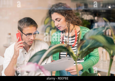 Moglie che mostra i documenti importanti il marito lavorando insieme Foto Stock