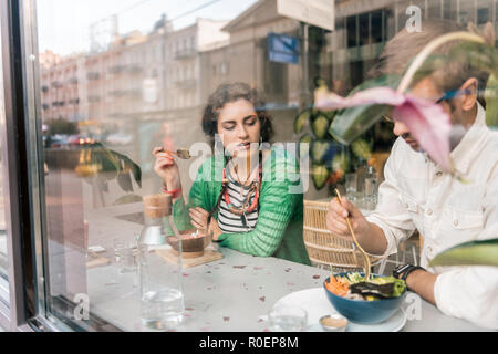 Carino amare giovane avente insieme per la prima colazione nell'accogliente caffetteria vegano Foto Stock