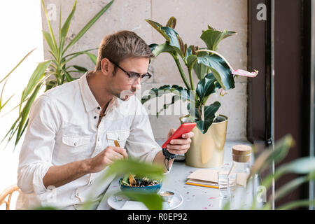 Duro lavoro di imprenditore controllare la sua posta elettronica sul telefono cellulare avente il pranzo Foto Stock