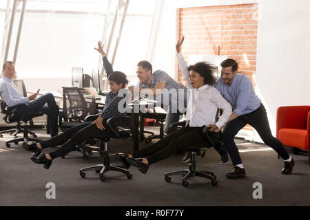 Carefree eccitato ufficio diversi lavoratori aventi fun riding oh cha Foto Stock