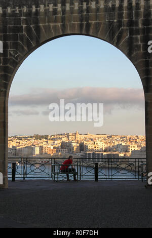 La Valletta, Malta - Maggio 2018: uomo sedersi sulla panchina di arco in Lower Barrakka Gardens durante il tramonto Foto Stock