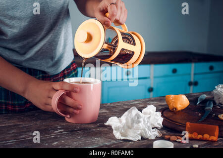 Tè nero versando in rosa cup da orange teiera Foto Stock