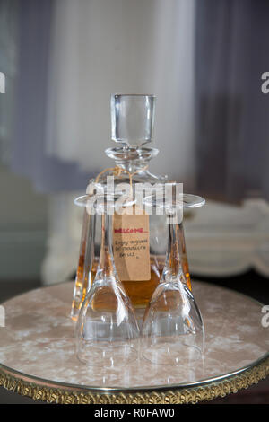 Due bicchieri puliti accanto alla metà di una bottiglia vuota di whiskey in una camera di hotel. Foto Stock