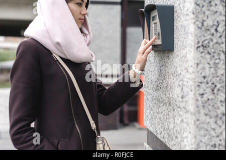 Brunette donna chiamate in interfono su strada, giorni di autunno in vestiti caldi Foto Stock