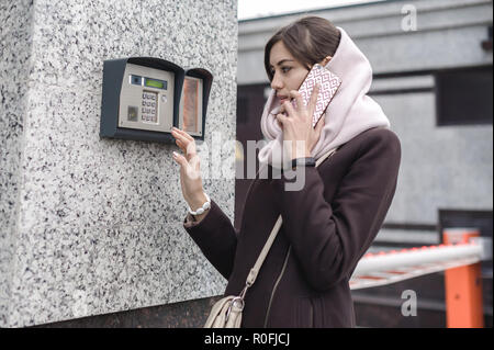 Brunette donna chiamate in interfono su strada, giorni di autunno in vestiti caldi Foto Stock