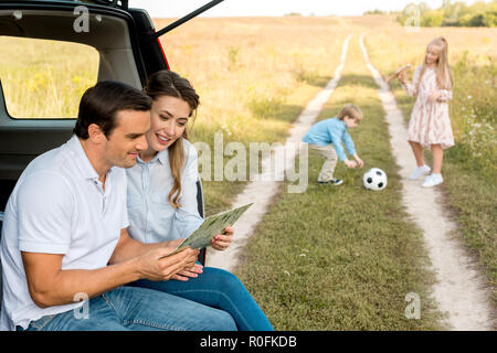 Felice giovane famiglia di trascorrere del tempo insieme in campo mentre viaggia in auto Foto Stock