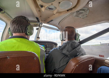 Pilota e co pilota di volare in un Piper PA-28 Cherokee aeromobili leggeri fuori di Northumbria Scuola di Volo, l'aeroporto di Newcastle, Tyne and Wear, Regno Unito Foto Stock