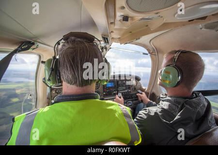 Pilota e co pilota di volare in un Piper PA-28 Cherokee aeromobili leggeri fuori di Northumbria Scuola di Volo, l'aeroporto di Newcastle, Tyne and Wear, Regno Unito Foto Stock