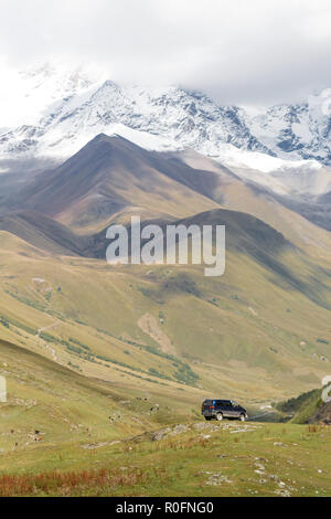 Lo splendido paesaggio di montagna in Georgia, con auto stare lontano. Cime coperte di neve sullo sfondo. Foto Stock