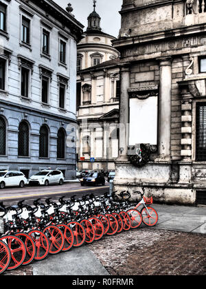 Lunga fila di biciclette con ruote di colore arancione in piazza della Scala. Milano, Italia Foto Stock