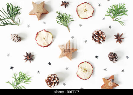 Christmas Festive composizione in stile. Motivo decorativo. Pigne, secchi Frutta apple, rami di cipresso, anice, coriandoli e stelle di legno isolato su bianco sullo sfondo di legno. Piatto, laici vista superiore Foto Stock