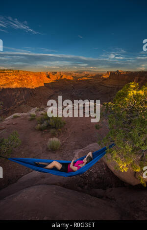 Escursionista poggia su una amaca ammirando il tramonto Oriente forcella Shafer Canyon nei pressi di Dead Horse Point State Park Canyonlands Utah Foto Stock