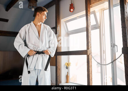 Le mani di serrare la cintura nera sull'uomo vestito di kimono Foto Stock