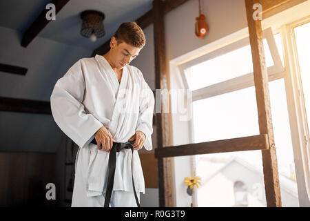 Le mani di serrare la cintura nera sull'uomo vestito di kimono Foto Stock