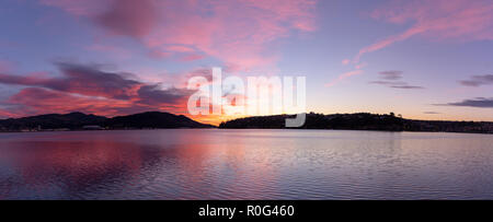 La mattina presto albe getta un glorioso bagliore rosa e riflessioni sul porto Foto Stock