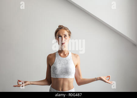 Giovane donna bionda vestita di bianco tank top mantenendo le dita nel gesto mudra Foto Stock