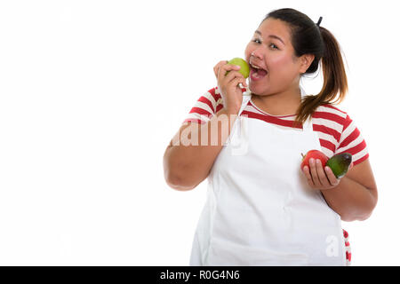 Studio shot di giovani felici fat Asian donna sorridente e mangiare gr Foto Stock