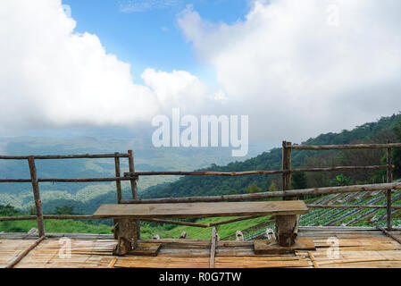 Sede rendono da legno per guardare la vista del paesaggio strawberry farm con sfondo di montagna e di cielo nuvoloso a ' Mon Jam ' Northside in Thailandia. Foto Stock