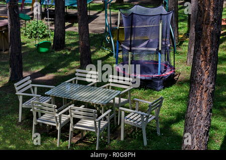 Estate bambini bivacco pubblica con tavolo sedie e Trampolino di salto nella foresta di conifere, vicino al villaggio di Pasarel, Bulgaria Foto Stock