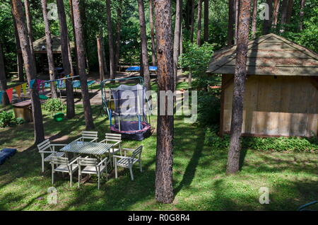 Estate bambini bivacco pubblica con tavolo, sedia, house e Trampolino di salto nella foresta di conifere, vicino al villaggio di Pasarel, Bulgaria Foto Stock