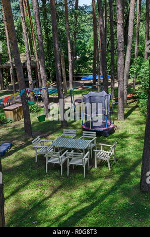 Estate bambini bivacco pubblica con tavolo, sedia, house e Trampolino di salto nella foresta di conifere, vicino al villaggio di Pasarel, Bulgaria Foto Stock