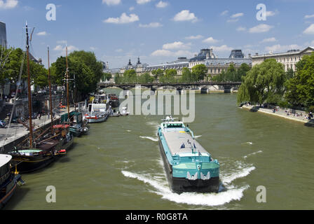 Chiatte a nolo trasportare merci sul fiume Senna passato ormeggiato a casa galleggiante e del museo del Louvre a Parigi, Francia. Foto Stock