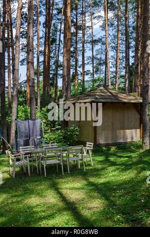 Estate bambini bivacco pubblica con tavolo, sedia, house e Trampolino di salto nella foresta di conifere, vicino al villaggio di Pasarel, Bulgaria Foto Stock