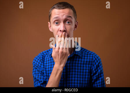 Studio shot del giovane uomo contro lo sfondo marrone Foto Stock