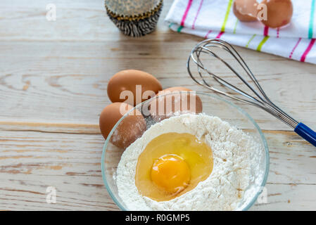 La cottura Ingredienti farina, uova con la frusta, con gusci di uova rotti sul tovagliolo. Foto Stock