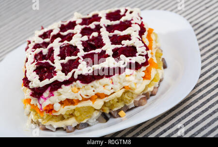 Insalata con dadini di stratificata aringhe in salamoia e grattugiato verdure bollite Foto Stock