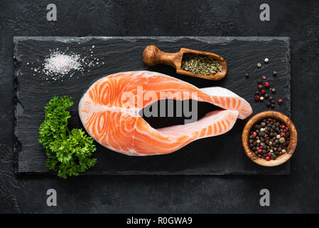 Raw bistecca di salmone e spezie su ardesia pronta per la cottura, vista dall'alto. Mangiare sano, paleo dieta concetto Foto Stock