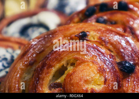 Un certo numero di appetitosi rubicondo arrotolato panini con uvetta in una vetrina Foto Stock