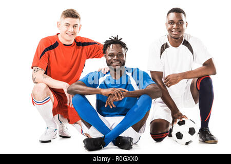 Allegro multietnica di giovani giocatori di calcio sorridente in telecamera isolato su bianco Foto Stock