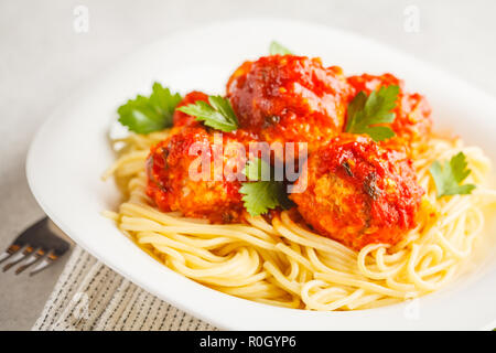 Polpette di pollo con salsa di pomodoro e gli spaghetti al dente in una piastra bianca, sfondo bianco. Foto Stock