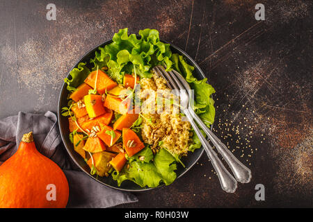 Riscaldare la quinoa e zucca insalata in una piastra bianca. Vegano sano concetto di cibo, dieta alimentare. Foto Stock