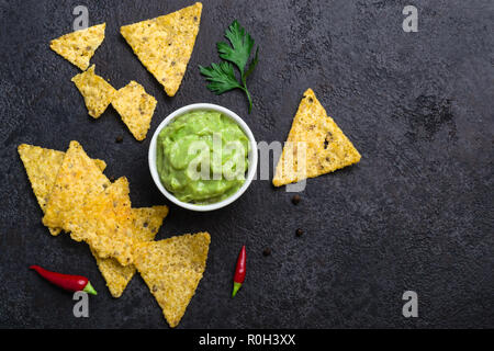 Tradizionale cibo messicano guacamole e corn chips su sfondo nero. Foto Stock