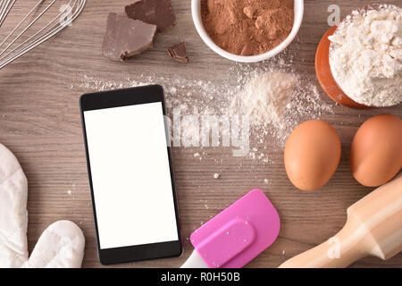 Gli ingredienti di pasticceria su una tavola di legno con mobile. Concetto di ricette nel libro digitale. Composizione orizzontale. Vista superiore Foto Stock