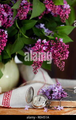 Bella composizione con bouquet di lilla e l'orologio Foto Stock