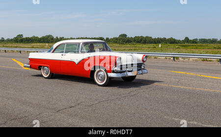 Leggere e bianco 1955 Ford Crown Victoria su una strada vuota. Foto Stock