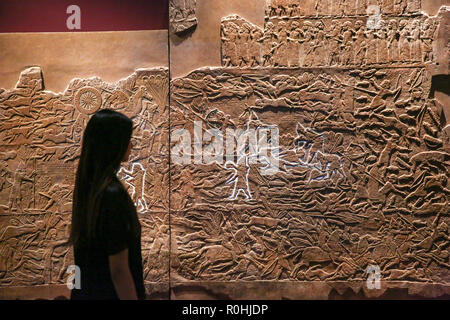 Londra, Regno Unito. 5 Novembre, 2018. Il British Museum. Un membro del personale guarda 'Battaglia di Til-Tuba' mostra presso il British Museum è sull antico Iraq nel VII secolo a.c. quando divenne Ashurbanipal la persona più potente sulla terra. Dalla sua capitale a Ninive, egli dominava un vasto e diversificato impero, sagomando la vita dei popoli dalle sponde del Mediterraneo orientale delle montagne dell'Iran occidentale. Credito: Dinendra Haria/Alamy Live News Foto Stock