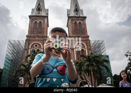 Un giovane ragazzo scattare foto davanti alla Cattedrale di Notre Dame di Saigon, Ho Chi Minh City, Vietnam. Foto Stock