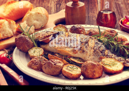 Dorada grigliata di pesce con patate arrosto e verdure sulla piastra, close up vista vintage Foto Stock