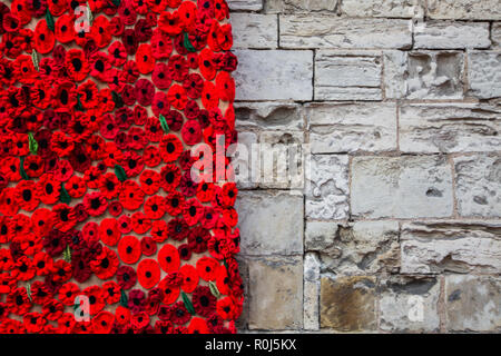 A mano a maglia papaveri decorare il muro di pietra di una chiesa per commemorare il centenario della guerra mondiale 1 in aiuto dell'appello di papavero Foto Stock