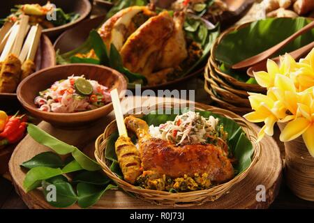 Il Nasi Campur Ayam Betutu. Pasto Balinese di riso al vapore con il piccante pollo arrosto (Ayam Betutu), saté, e verdure Foto Stock