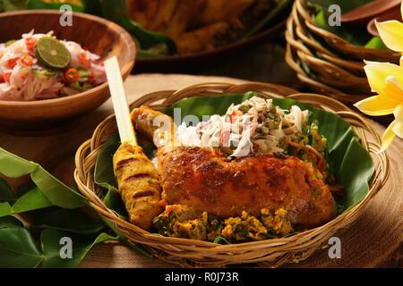 Il Nasi Campur Ayam Betutu. Pasto Balinese di riso al vapore con il piccante pollo arrosto (Ayam Betutu), saté, e verdure Foto Stock