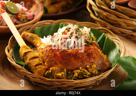 Il Nasi Campur Ayam Betutu. Pasto Balinese di riso al vapore con il piccante pollo arrosto (Ayam Betutu), saté, e verdure Foto Stock