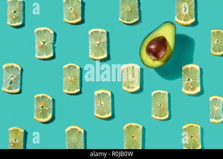 Modello realizzato di fette di limone e metà avocado su uno sfondo blu. Sfondo di cibo. Lay piatto Foto Stock